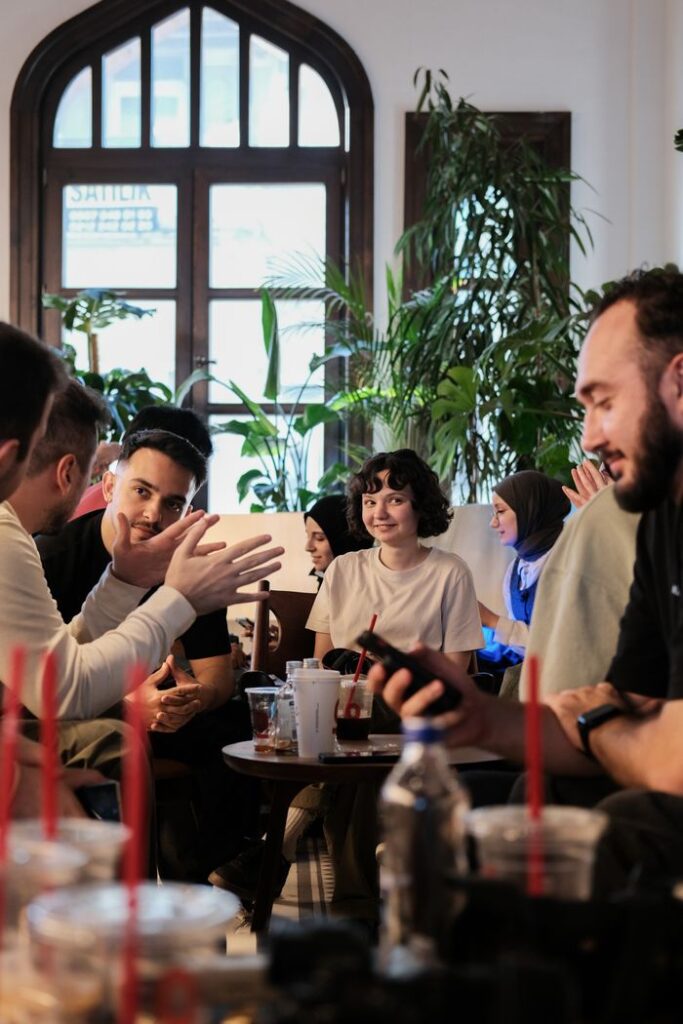 Group of friends enjoying a casual chat in a cozy cafe setting; vibrant and warm atmosphere.