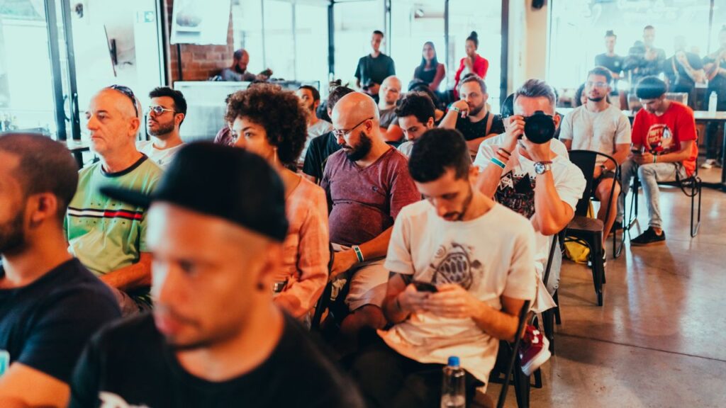 Diverse group of people attending a modern conference, engaged in listening and discussions.
