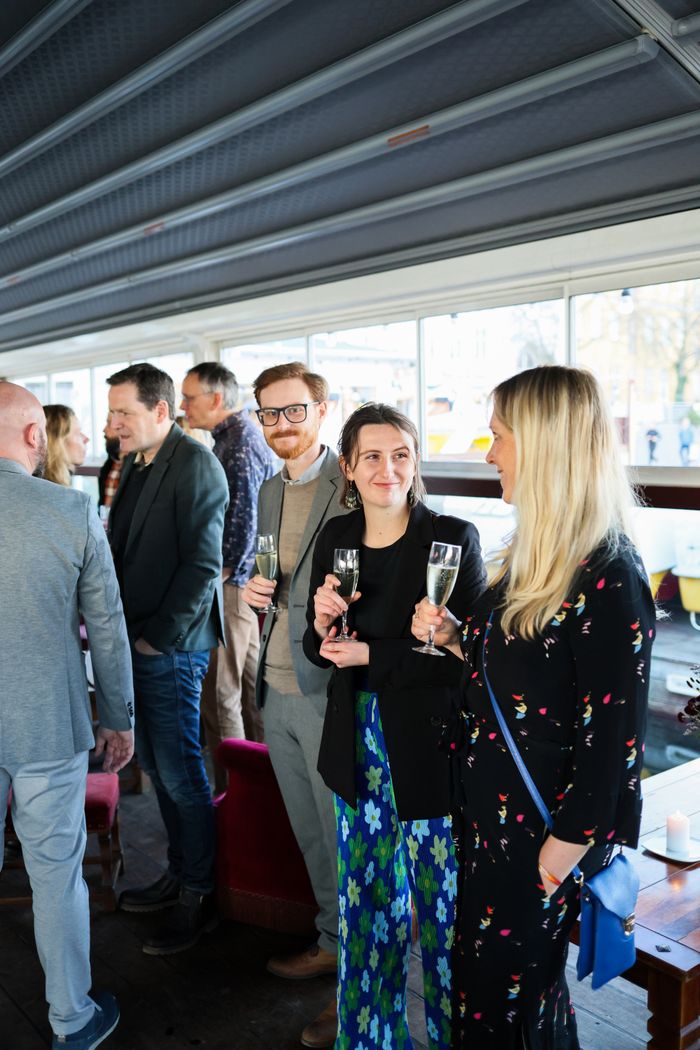 Group of adults socializing with drinks at a casual indoor gathering.