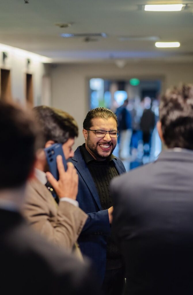A group of professionals engaging in conversation at a networking event indoors.